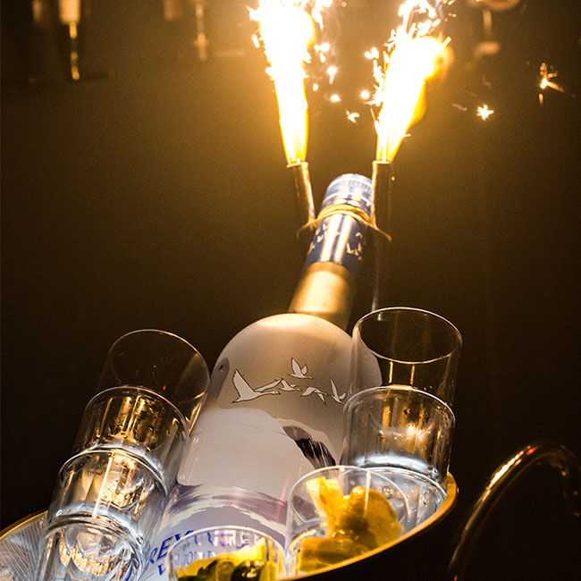 close up of a liquor bottle with fireworks and glasses around it lansing mi